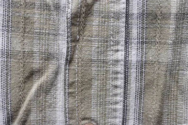 Close up part of a shirt from hemp fabric. Casual man\'s shirt with pattern. Wrinkled texture from hemp and cotton background