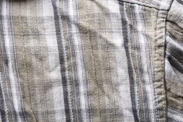 Close up part of a shirt from hemp fabric. Casual man\'s shirt with pattern. Wrinkled texture from hemp and cotton background