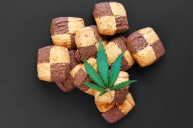 Hemp biscuits on a dark background with a green leaf of cannabis clipart