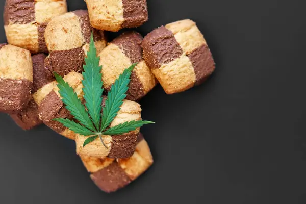 Hemp biscuits on a dark background with a green leaf of cannabis — Stock Photo, Image