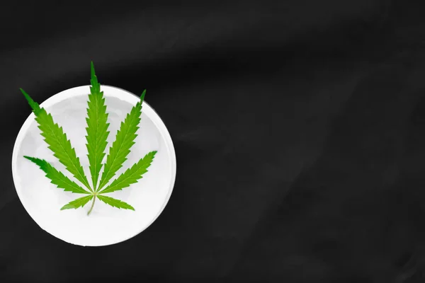 Top view of a jar with CBD or hemp salve with cannabis leaf on b