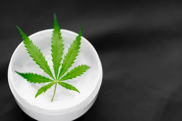 Top view of a jar with CBD or hemp salve with cannabis leaf on b