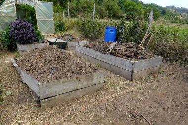 El arabası, aletler ve toprak ve gübre dolu bahçe yatakları çiftçilik ve bahçıvanlık faaliyetlerini gösteriyor.
