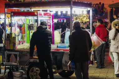 Thessaloniki, Yunanistan - 24 Aralık 2018: Aristotelous square, yerel Yunan street satıcı. Işıklı römork pamuk şeker, kestane veya patlamış mısır satan etrafında Kalabalık cadde görünümü akşam.