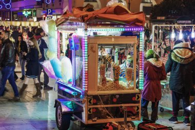 Thessaloniki, Yunanistan - 24 Aralık 2018: Aristotelous square, yerel Yunan street satıcı. Işıklı römork pamuk şeker, kestane veya patlamış mısır satan etrafında Kalabalık cadde görünümü akşam.