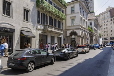 Milan, İtalya - 12 Mayıs 2018: Via Monte Napoleone lüks alışveriş caddesi ile lüks arabalar. Milano Moda Bölgesi Dolce ve Gabbana yüksek son özel butik dışındaki kişiler.