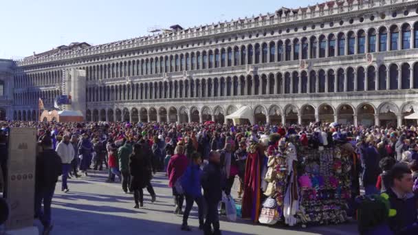カーニバル中に大規模な群衆の中にヴェネツィア イタリア 2019 サンマルコ広場 ピアッツァ マルコで露店販売マスクやヴェネツィアのカーニバルのお祝いの時に記念品の人々 — ストック動画