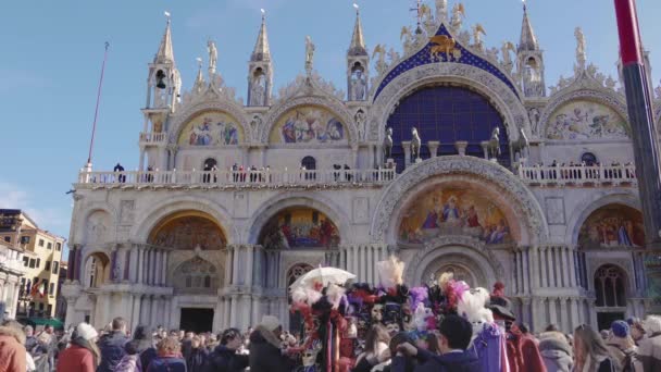 カーニバル中に大聖堂の前に群衆の中にヴェネツィア イタリア 2019 サンマルコ広場 ヴェネツィアのカーニバルのお祝いの中にピアッツァ マルコでの人々 とバシリカ マルコ ファサード — ストック動画