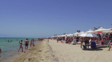 Chalkidiki, Yunanistan-Haziran 09 2019: Yunan Akdeniz plaj bar kalabalık ile. Halkidiki Kassandra Yarımadası 'nda mavi gökyüzü altında bir aile kumsalında güneş şemsiyeleri ve şezlong ile bathers, Yunanistan.