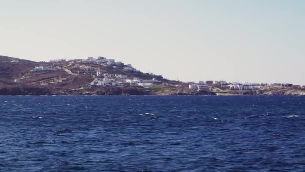 ギリシャのキクラデス諸島の風景は ミコノス島の丘の上に家を白塗りしました ミコノスタウンから見た低層の伝統的なミコネアンの白い家の日の海の眺め — ストック動画
