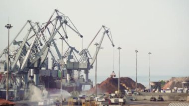 Deniz limanında büyük motorlu vinçler gemilerden kargo boşaltma. Selanik Limanı'nın ticari rıhtım iskelesinde kargo taşıma gemi kıyı vinçler yükseltilmiş görünümü, Yunanistan.