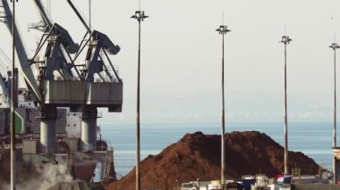 Deniz limanında büyük motorlu vinçler gemilerden kargo boşaltma. Selanik Limanı'nın ticari rıhtım iskelesinde kargo taşıma gemi kıyı vinçler yükseltilmiş görünümü, Yunanistan.
