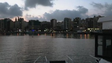 Sliema feribotuna Valletta Malta 'da rıhtıma yaklaşıyor. Malta başkenti sık feribot servisi yapan Katamaran gemi görülen modern binalar ile Sliema sahil gezinti gece görünümü.