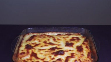 Yunan musakka yemeği tarifi hazırlama. Beşamel beyaz sos ile pişmiş mousaka porsiyon şeffaf bir kase üzerinde dikey kaydırma atış, zemin doğranmış sığır eti üzerinde kızarmış doğranmış patates.