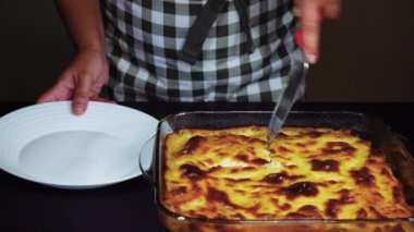 Yunan musakka yemeği tarifi hazırlama. Şeffaf bir kaseden el beşamel beyaz sos lu pişmiş bir mousaka porsiyon, kıyma kıyma üzerinde kızarmış doğranmış patates.