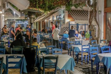 Selanik, Yunanistan - 12 Ekim 2019: Açık hava taverna restoranlarında insanların Yunan gece hayatı sahnesi. Athonos bölgesindeki tavernalarda yemek yiyen ve içen kimliği belirsiz kalabalık.