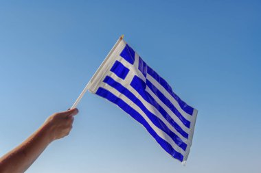 Ulusal bir kutlama için havada Yunan bayrağı sallıyor. 28 Ekim 1940 'da Mussolini İtalyan ültimatomuna karşı düzenlenen Oxi Günü' nü kutlayan haçlı mavi ve beyaz Yunan plastik bayrağı..