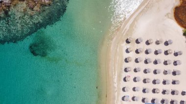 Akdeniz arazisi, Yunan manzaralı kumlu kumlu deniz dronu görüntüsü. Sithonia Chalkidiki yarımadasının gökyüzü manzarası kristal berrak sular ve şemsiyeli deniz yatakları küçük kayalık adanın yanında..