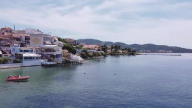 Chalkidiki, Yunan sahil köyünün insansız hava aracı görüntüsü. Düşük katlı binalar ve arka planda Porto Carras tatil beldesi bulunan Sithonia yarımadasındaki Neos Marmaras 'ın hava günü görüntüsü.