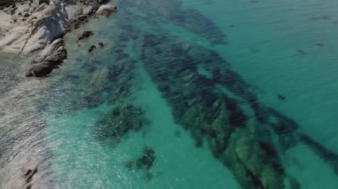 Akdeniz 'in insansız hava araçları Kavourotripes plajında yüzücülerle çekim yapıyor. Sithonia Chalkidiki yarımadası, kayalık kıyı şeridinden kristal berrak su yataklarına şemsiyeli hava manzaralı.