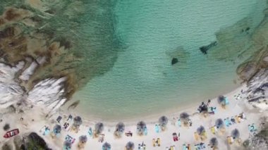 Akdeniz 'in insansız hava araçları Kavourotripes plajında yüzücülerle çekim yapıyor. Sithonia Chalkidiki yarımadası, şemsiyeli deniz yataklarından kristal berrak sulara sahip kayalık kıyılara kadar havadan manzaralı tava..