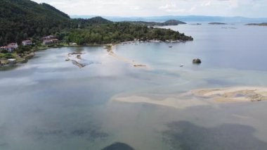 Akdeniz Yunanistan 'ın kıyı insansız hava aracı görüntüsü. Sithonia Chalkidiki yarımadasının havadan görünüşü denizden kıyı şeridine yeşil tarlalar ve kırsal yolun yanındaki evleri gösteriyor..