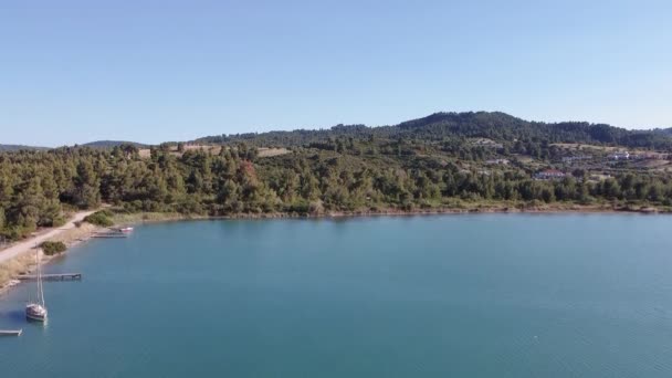 地中海希腊海岸无人驾驶飞机与停泊的船只射击 Kassandra Chalkidiki半岛Glarokavos泻湖的空中俯瞰 岛上有绿色种植园和房屋 — 图库视频影像