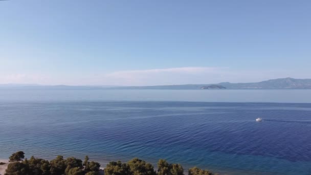 无人驾驶飞机在希腊平静的海面上拍到了渔船的照片 Kassandra Chalkidiki半岛海岸线上有绿色种植园的斜向航行的空中俯瞰 — 图库视频影像