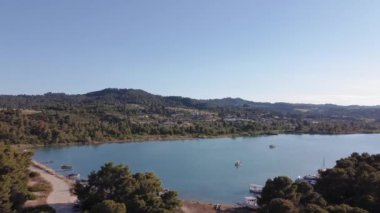 Akdeniz kıyısı insansız hava aracı, çam kaplı tepe evlerinin bulunduğu bölgeye düştü. Kassandra Chalkidiki yarımadasındaki Glarokavos lagününün yeşil plantasyonlu ve demirli tekneleriyle kıyı şeridinin üzerindeki hava manzarası.