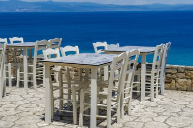 Yunanistan 'ın Chalkidiki kenti, yeni covid-19 tedbirleri sonrasında bar ahşap sandalye ve masaları boşalttı. Athytos, Kassandra yarımadasında müşterisi olmayan deniz manzaralı bir restoran..