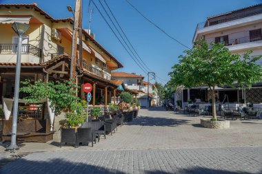 Yunanistan 'ın Chalkidiki kenti, yeni covid-19 tedbirleri sonrasında neredeyse kafe sandalye ve masalarını boşaltıyordu. Kassandra yarımadasındaki Hanioti köyü meydanında birkaç müşteriyle açık hava oturma alanı..