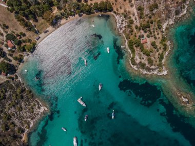 Akdeniz kıyısı insansız hava aracı, demirli eğlence tekneleriyle çekiliyor. Sithonia Chalkidiki yarımadasının yeşil plantasyonu ve kristal berrak denizi ile üst sahil üzerindeki hava günü manzarası.