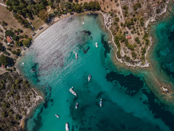 Akdeniz kıyısı insansız hava aracı, demirli eğlence tekneleriyle çekiliyor. Sithonia Chalkidiki yarımadasının yeşil plantasyonu ve kristal berrak denizi ile üst sahil üzerindeki hava günü manzarası.
