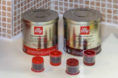 Espresso yapımında kullanılan tek katmanlı Iperespresso kapsülleri. Şirket logosu ve beyaz bir bankta sıcak damlayan kahve yapmak için metal kılıflı klasik ve yoğun tatlandırıcı kapsüller..