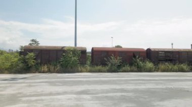 Eski lokomotifli terk edilmiş ticari vagonların hava aracı manzarası. Yunanistan 'ın Selanik kentinde bir demiryolu rayına park edilmiş nakliye araçları için kullanılan mallarla bağlantılı en üst panorama.