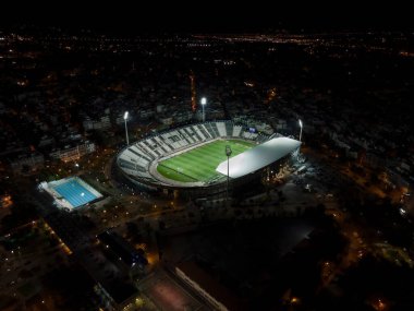 Selanik, Yunanistan PAOK FC Toumba stadyumunun çimenli insansız hava aracı görüntüleri. Tribünlerde taraftarları olmadan futbol sahası ve takım adının yazılı olduğu havadan en iyi gece görüntüsü.