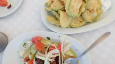 Yunan tavernası meze başlangıç yemeği yakın plan. Taze patates, midye, beyaz soslu kızarmış kabak ve beyaz masa örtülü bir restoran masasında balık filetosu..