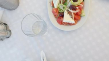 Bir grup arkadaş restoranın üst katında kadeh kaldırıyor. Meyhane masasının üstünde Yunan salatası ve balık mezesi başlangıç yemeğiyle bir bardak alkollü uzo içeceği içen insanlarla sosyal bağ kurmak..