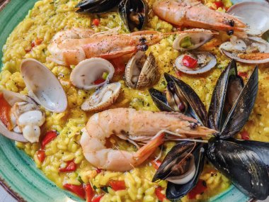 Kabuklu deniz ürünleri ve safranlı bir tabakta pişmiş karides. POV servis edilen deniz taraklarını kapat ve midyeleri aç..