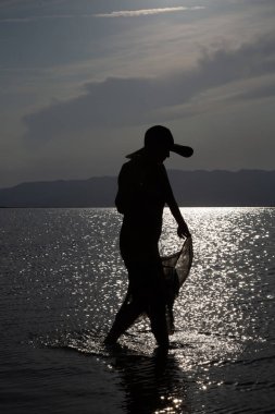 Sahilde dikey ışıkta şapkalı bir kadın.