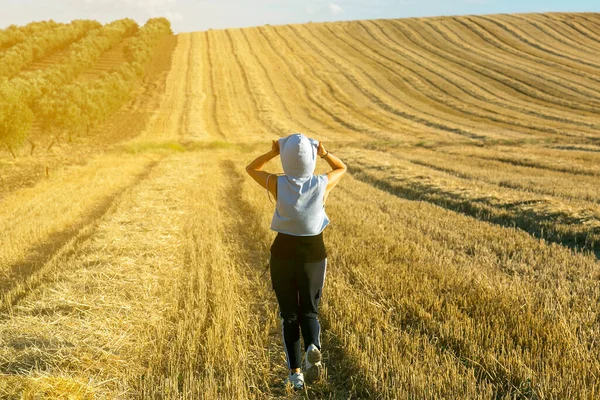 Sportief meisje loopt door het droge gras van het veld — Stockfoto