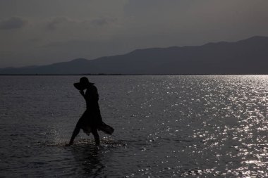 Suyla oynayan kadın, Ebro deltasındaki ışığa karşı oynuyor.