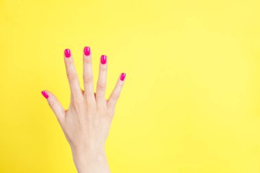 Güzel bir manikür, yazı için boşluk, düz yatak. Sarı arka planda genç bir kadının güzel eli. 