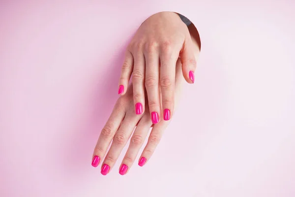 Beautiful manicure close-up. Beautiful hands of a young woman on a pink background.