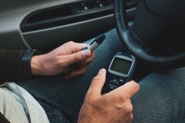Diyabet hastası arabada kan şekeri seviyesini ölçüyor, diyabet konseptini kapatıyor..