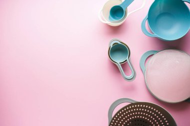 Pembe arka planda yazı için alanı olan çeşitli mutfak aletleri. En üstteki kase kümesi.