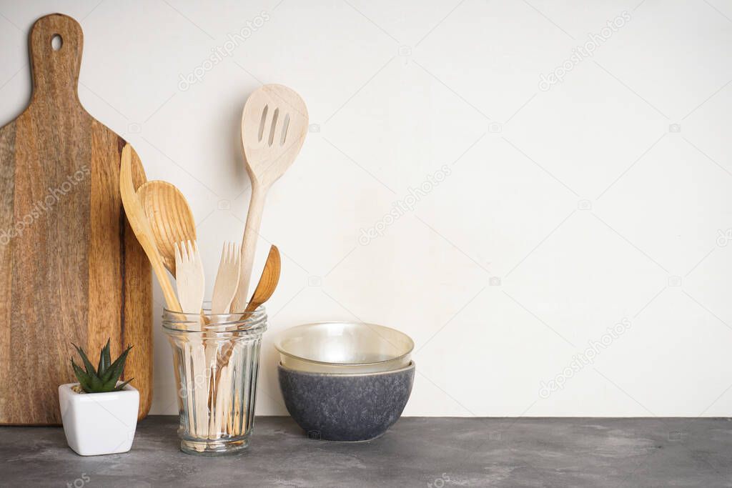 Wooden kitchen utensils in a glass on a gray background with place for text.