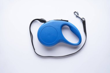 Beyaz arka planda mavi geri çekilebilir köpek tasması. Düz yatıyordu.