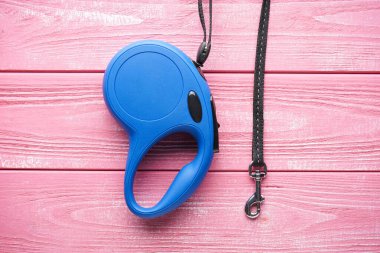 Mavi geri çekilebilir köpek tasması ahşap pembe arka plan, yazı için boşluk. Düz yatıyordu.