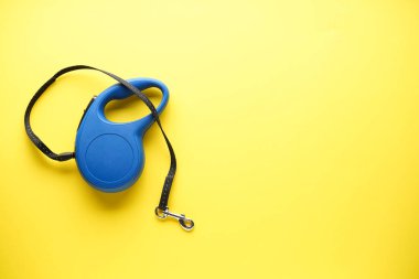 Blue retractable dog leash on a yellow background, with space for text. Top view. clipart